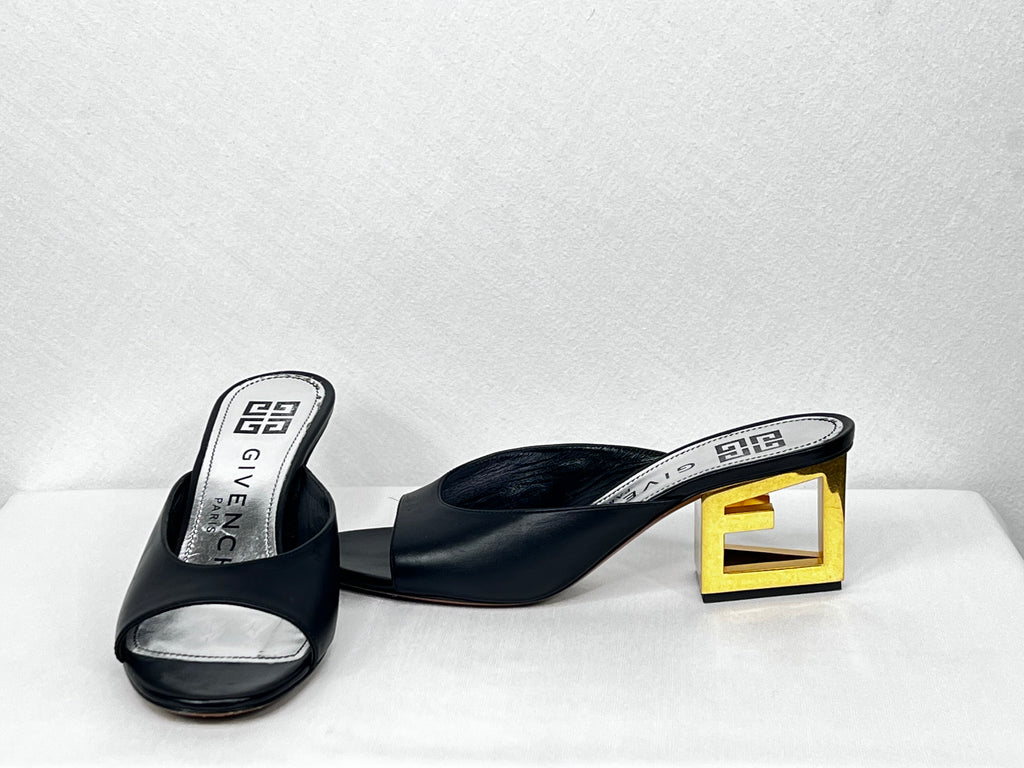 Pre-owned Givenchy black leather open-toe mules featuring sculptural gold block heel, angled view