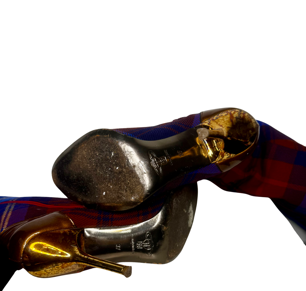 Close-up of soles on Vivienne Westwood tartan over-the-knee boots showing embossed branding and signs of gentle pre-owned wear.