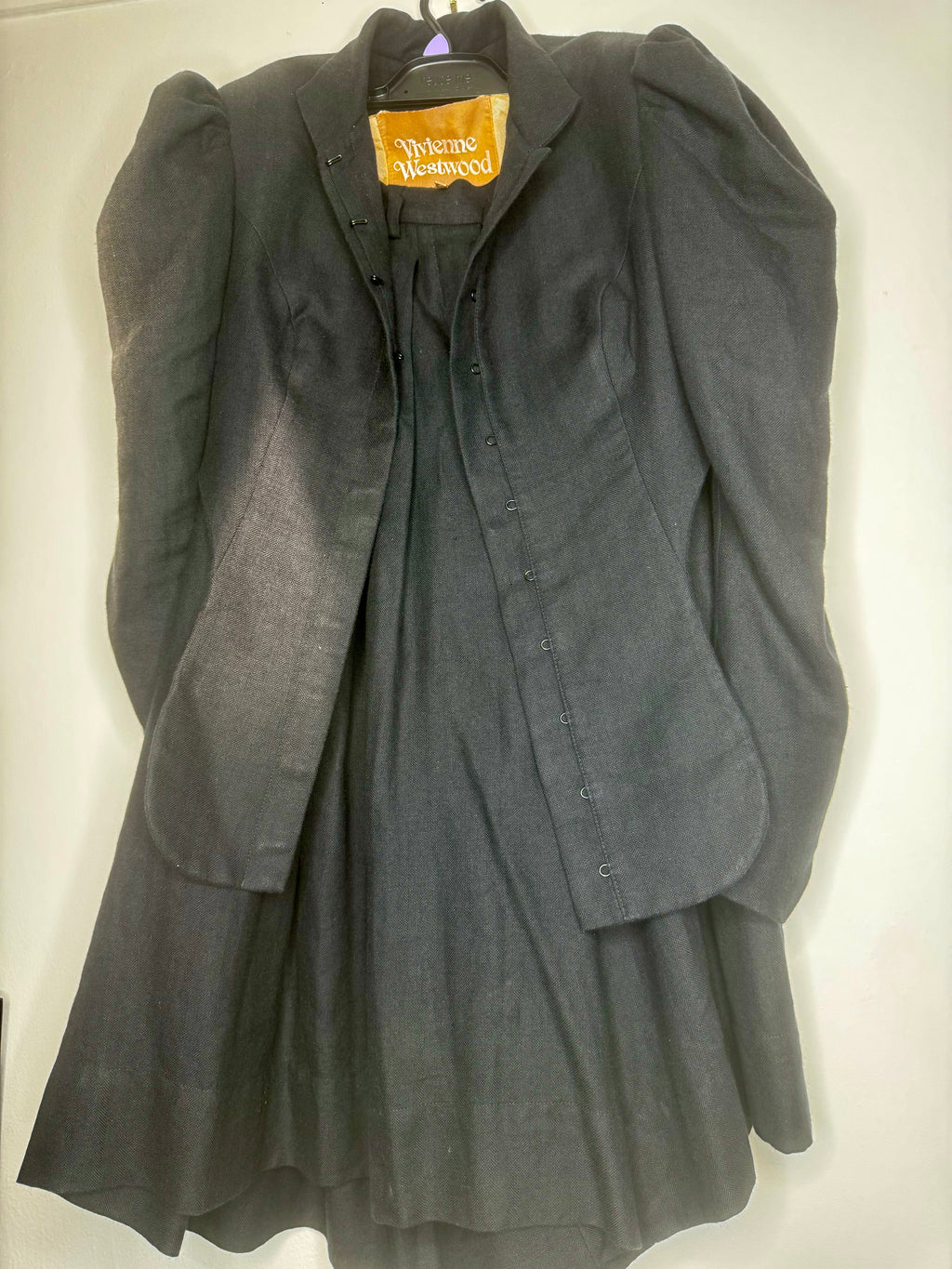 Close-up of black fabric texture on a vintage Vivienne Westwood jacket and culotte set, showing natural wear consistent with age.
