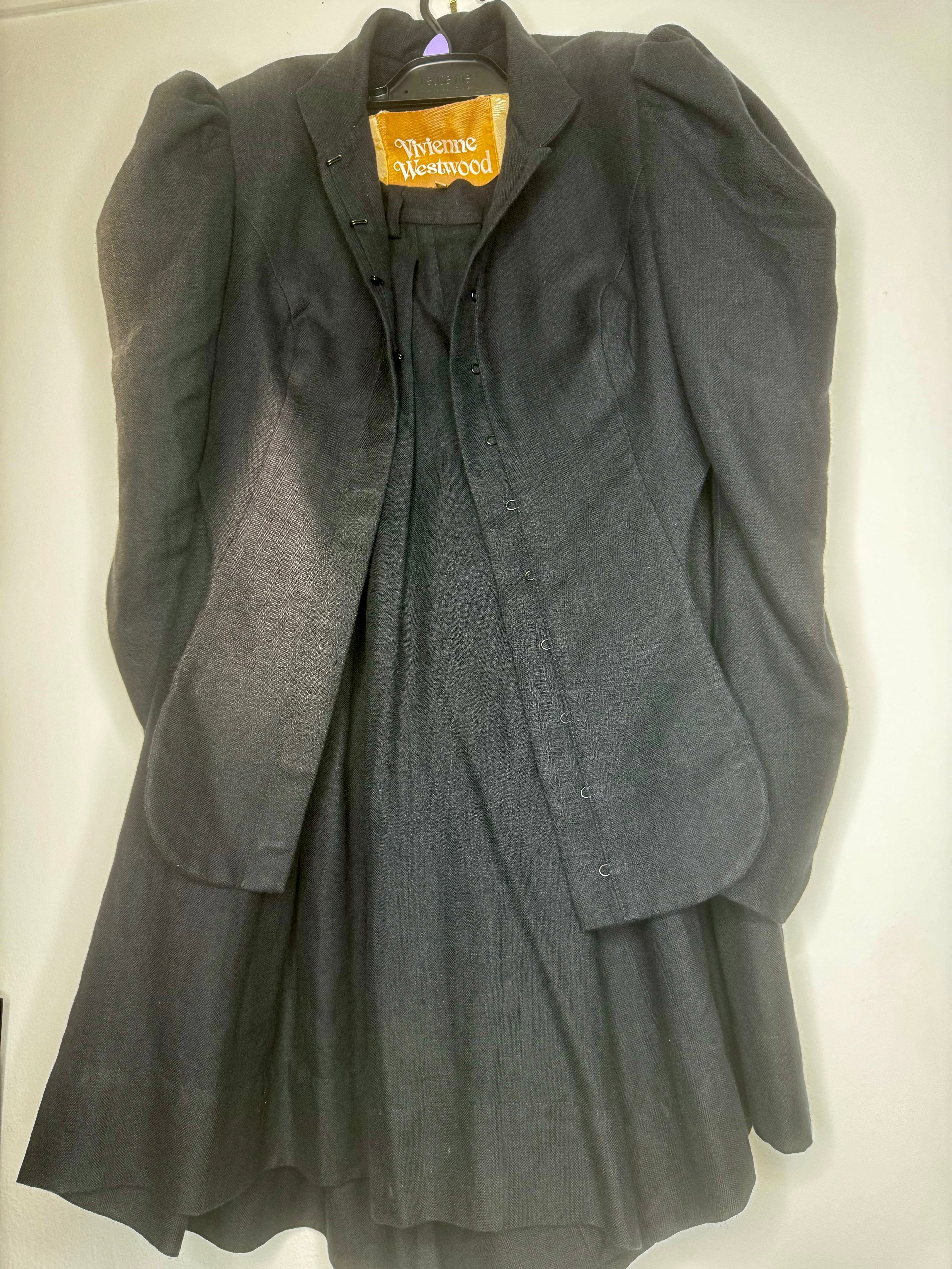 Close-up of black fabric texture on a vintage Vivienne Westwood jacket and culotte set, showing natural wear consistent with age.