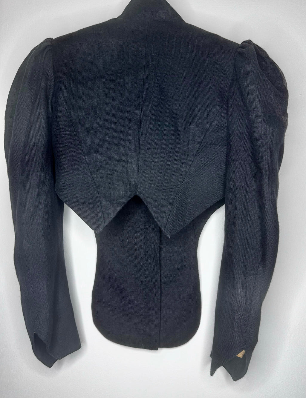 Back view of vintage Vivienne Westwood cropped black jacket highlighting angular cropped hem and sculpted tailoring.