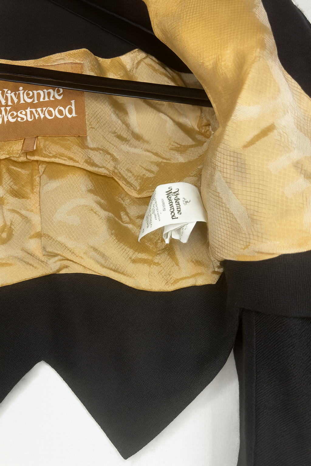 Interior label and gold jacquard lining of a vintage Vivienne Westwood jacket, showing designer branding and craftsmanship.